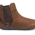 A stylish brown ankle-high leather Chelsea Boot from Xero Shoes, featuring a pull tab at the back, elastic side panel, and dark rubber sole. This modern design also includes a small strap detail near the heel for added flair.